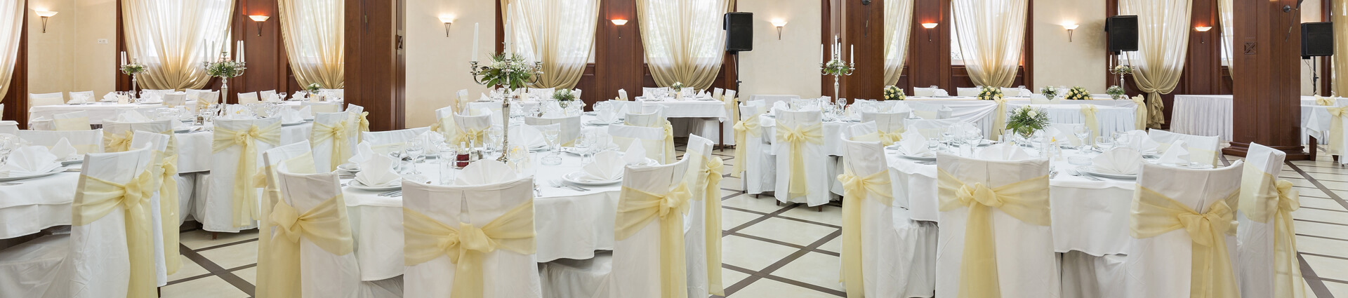 Beautiful wedding banquet hall decorated with elegant drapes, chandeliers, and floral arrangements with soft natural lighting