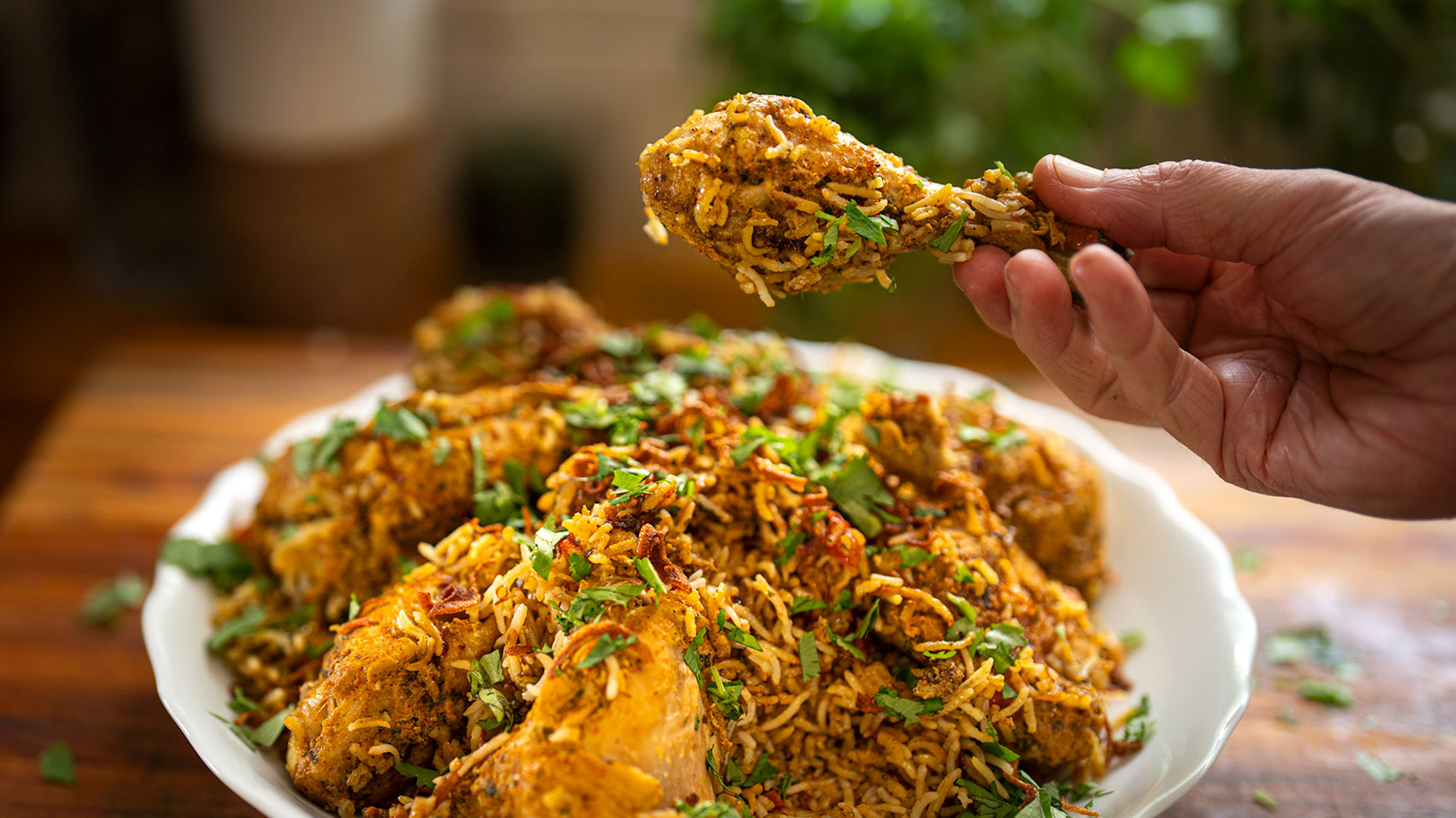 Plate of chicken biryani served in a traditional bowl with garnished mint leavess and fried onions