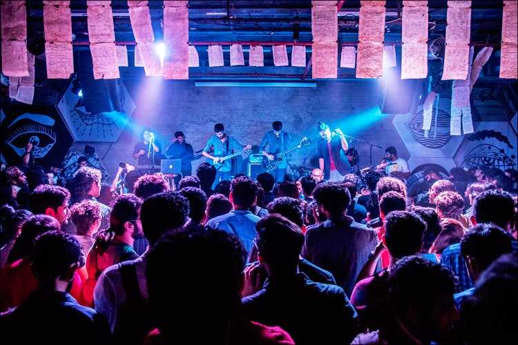 DJ spinning music with colorful lights and crowd dancing in a lively nightclub