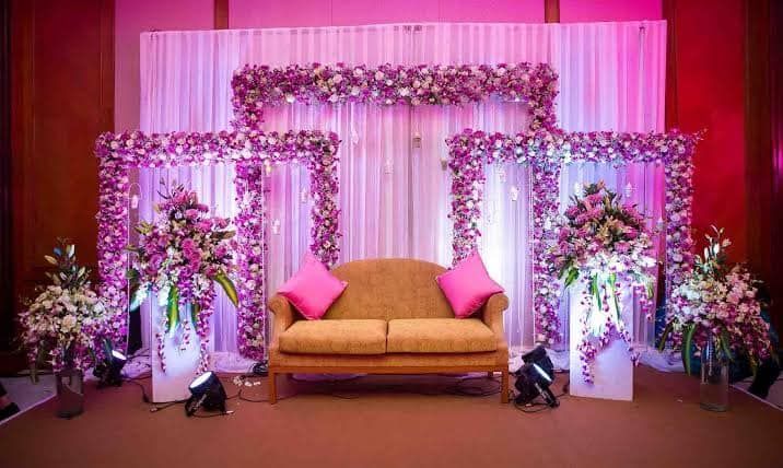 Bride and groom in colorful traditional attire performing wedding rituals with floral decorations and joyful family
